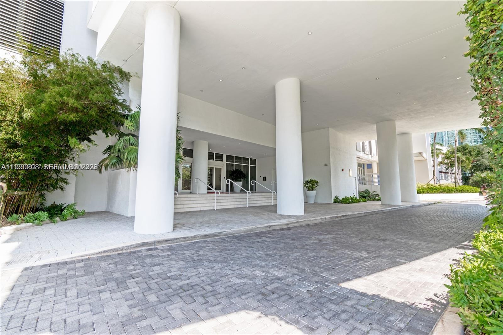 A covered driveway leads to the white entrance of a building with large support columns — 4250 NE Biscayne Blvd # 1115, Miami FL 33137, MIAMI, FL