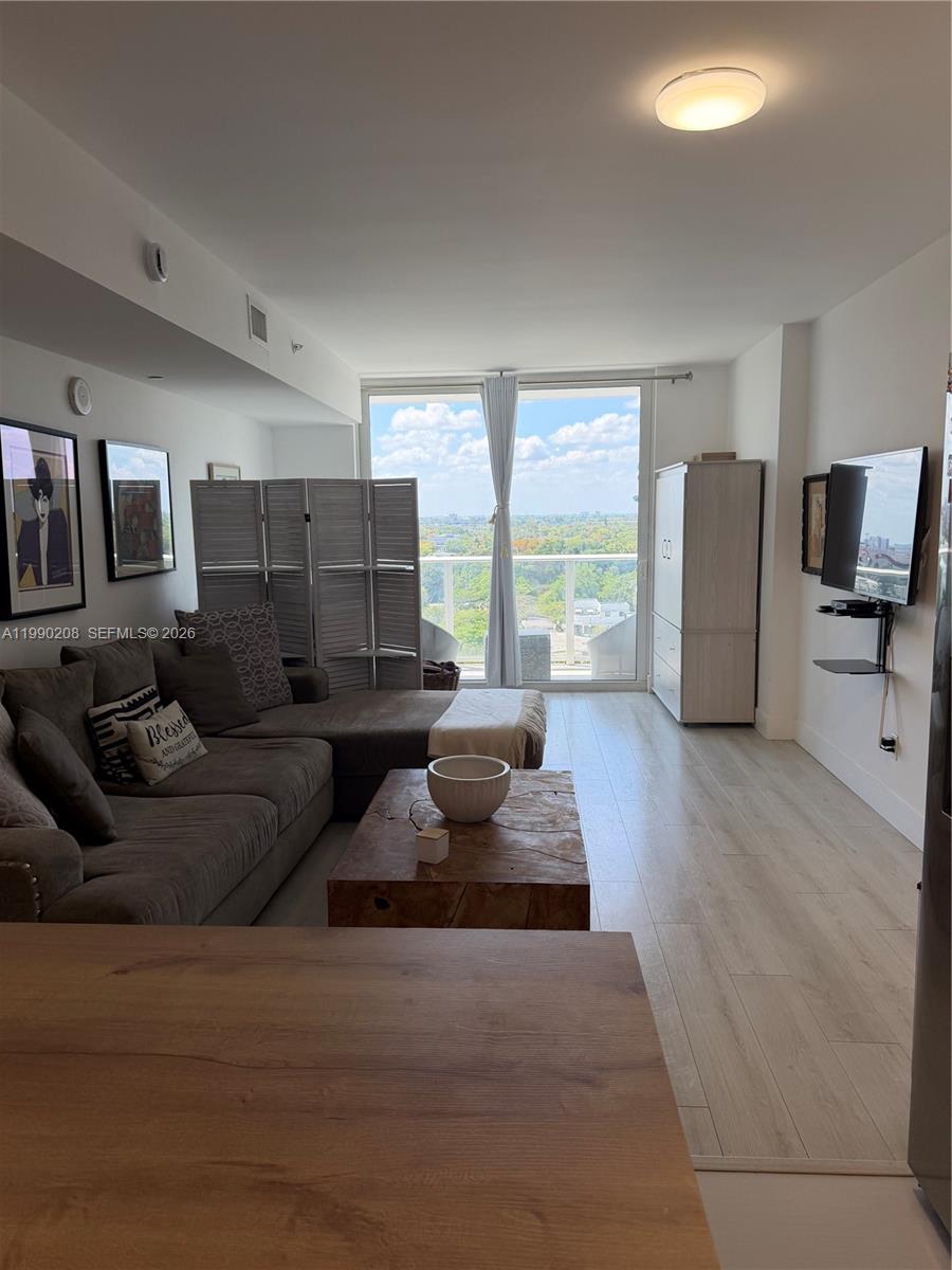 A living room features a gray sectional sofa, a wooden coffee table, and a balcony view — 4250 NE Biscayne Blvd # 1115, Miami FL 33137, MIAMI, FL
