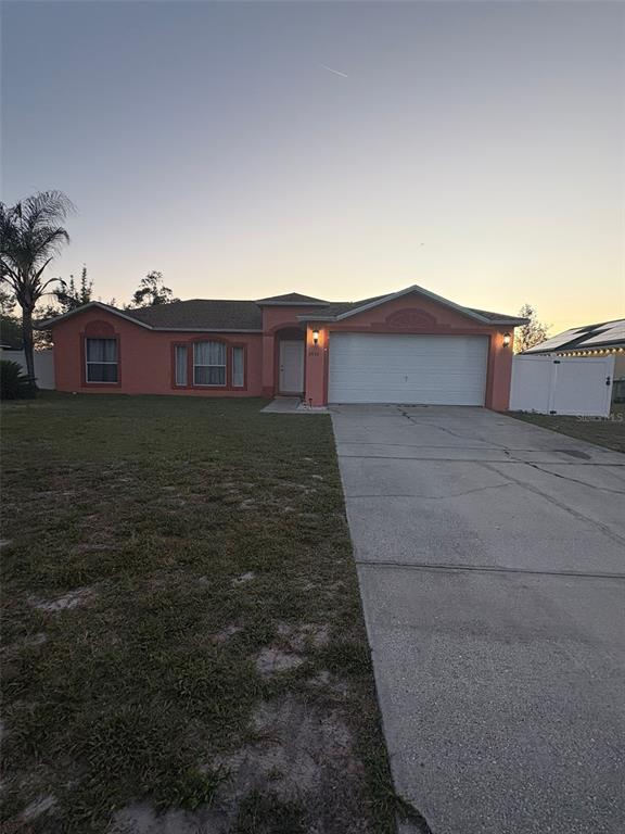 A single-story house with a peach-colored exterior, a two-car garage, and a concrete driveway — 2436 COURTLAND BOULEVARD, DELTONA, FL