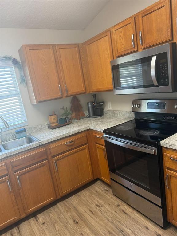 A kitchen features wood cabinets, stainless steel appliances, and light-colored countertops — 2436 COURTLAND BOULEVARD, DELTONA, FL