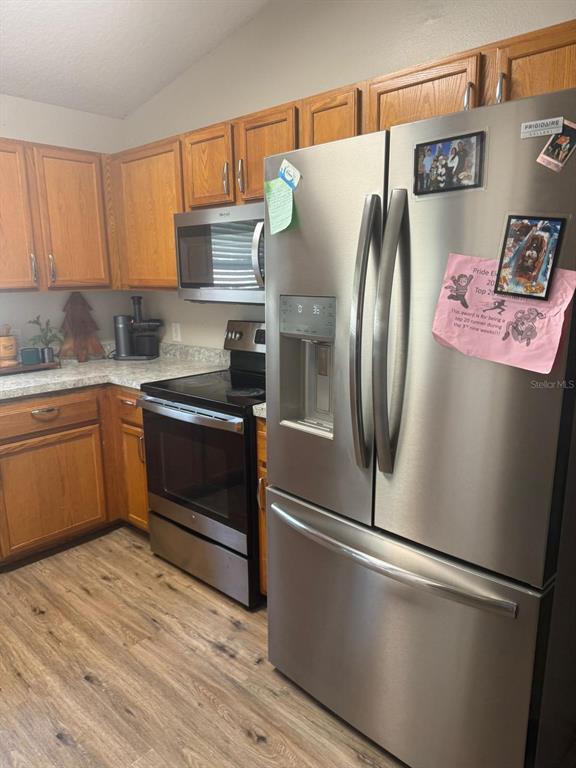 A kitchen features oak cabinets, stainless steel appliances, and light wood-look flooring — 2436 COURTLAND BOULEVARD, DELTONA, FL