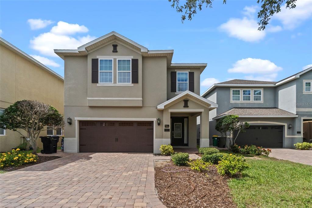 A two-story house with a beige stucco exterior, a paved driveway, and a two-car garage — 551 LASSO DRIVE, KISSIMMEE, FL