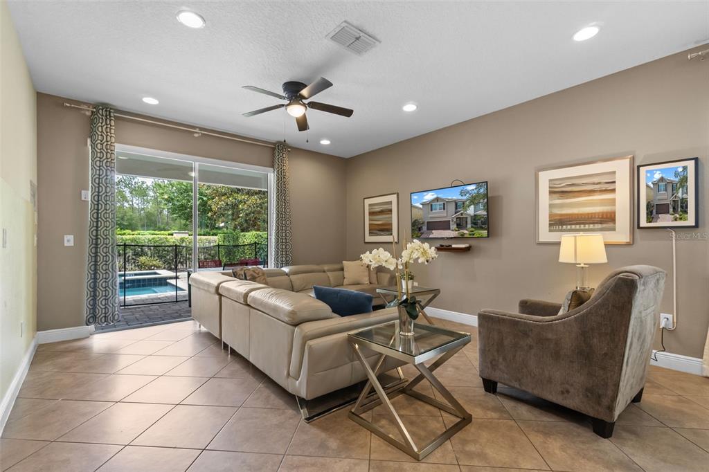 A living room features a beige sectional sofa, a glass-topped table, and a sliding door view — 551 LASSO DRIVE, KISSIMMEE, FL