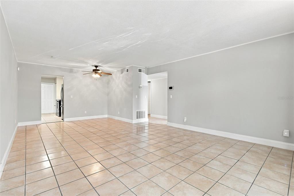 A spacious, empty room with light gray walls, white trim, and tan tiled flooring — 605 NORTHLAKE BOULEVARD UNIT 33, ALTAMONTE SPRINGS, FL