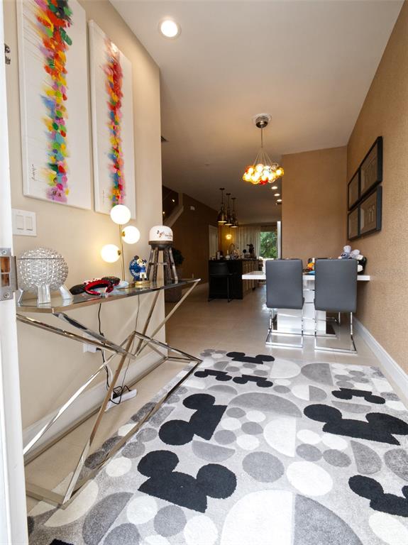 A modern entryway with a glass console table leads into a dining area and kitchen — 7671 RECIFE DRIVE UNIT 13-88, KISSIMMEE, FL