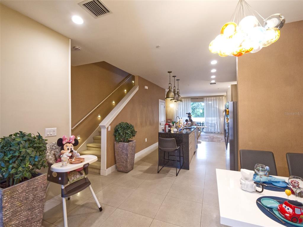 An open-concept kitchen and dining area features a staircase, a kitchen island, and tiled floors — 7671 RECIFE DRIVE UNIT 13-88, KISSIMMEE, FL