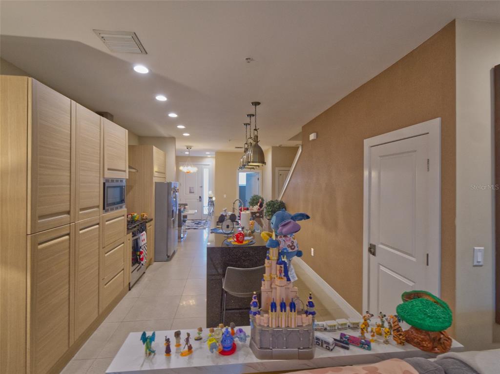 A kitchen with light wood cabinets, a dark island, and a collection of Disney toys — 7671 RECIFE DRIVE UNIT 13-88, KISSIMMEE, FL