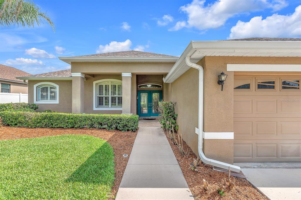 A tan house exterior features a concrete walkway leading to a teal double front door — 2817 DURANT TRAILS BOULEVARD, DOVER, FL