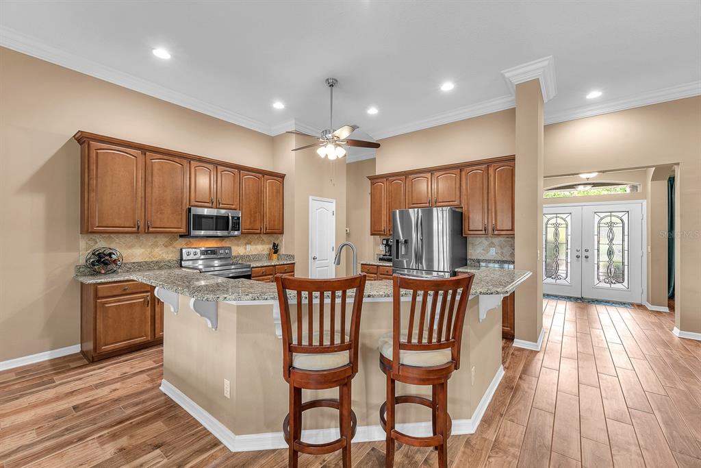 A kitchen features wood cabinets, granite countertops, a breakfast bar with stools, and tile flooring — 2817 DURANT TRAILS BOULEVARD, DOVER, FL