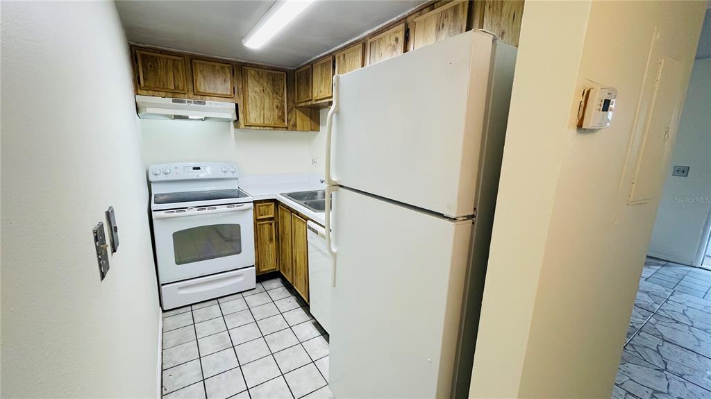 An empty room features tiled flooring, white walls, two windows with blinds, and a door — 7120 WATERSIDE DRIVE UNIT 106, TAMPA, FL