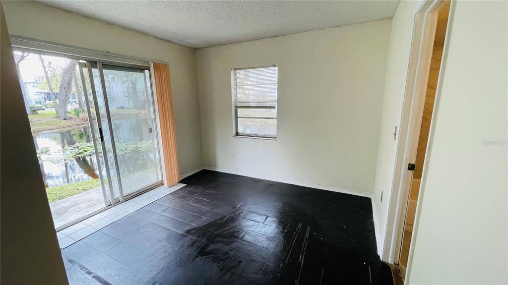 An empty room with dark wood-look flooring, a sliding glass door, and a single window — 7120 WATERSIDE DRIVE UNIT 106, TAMPA, FL