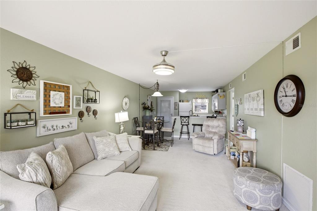A living room with light green walls, a sectional sofa, and an adjacent dining area — 25100 SANDHILL BOULEVARD UNIT G103, PUNTA GORDA, FL