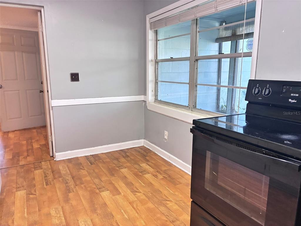 A kitchen area features wood-look flooring, gray walls with white trim, and a black stove — 120 CLUB ROAD, SANFORD, FL