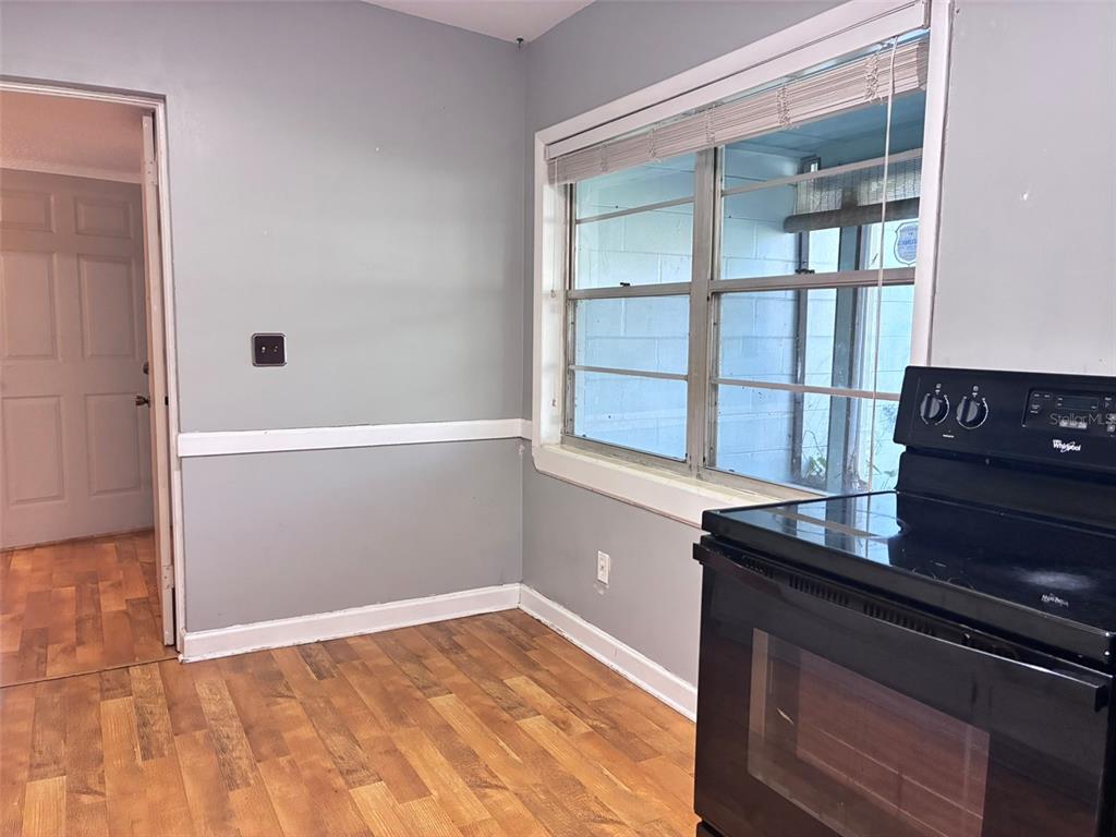 A kitchen area features light gray walls, wood-look flooring, a window, and a black stove — 120 CLUB ROAD, SANFORD, FL