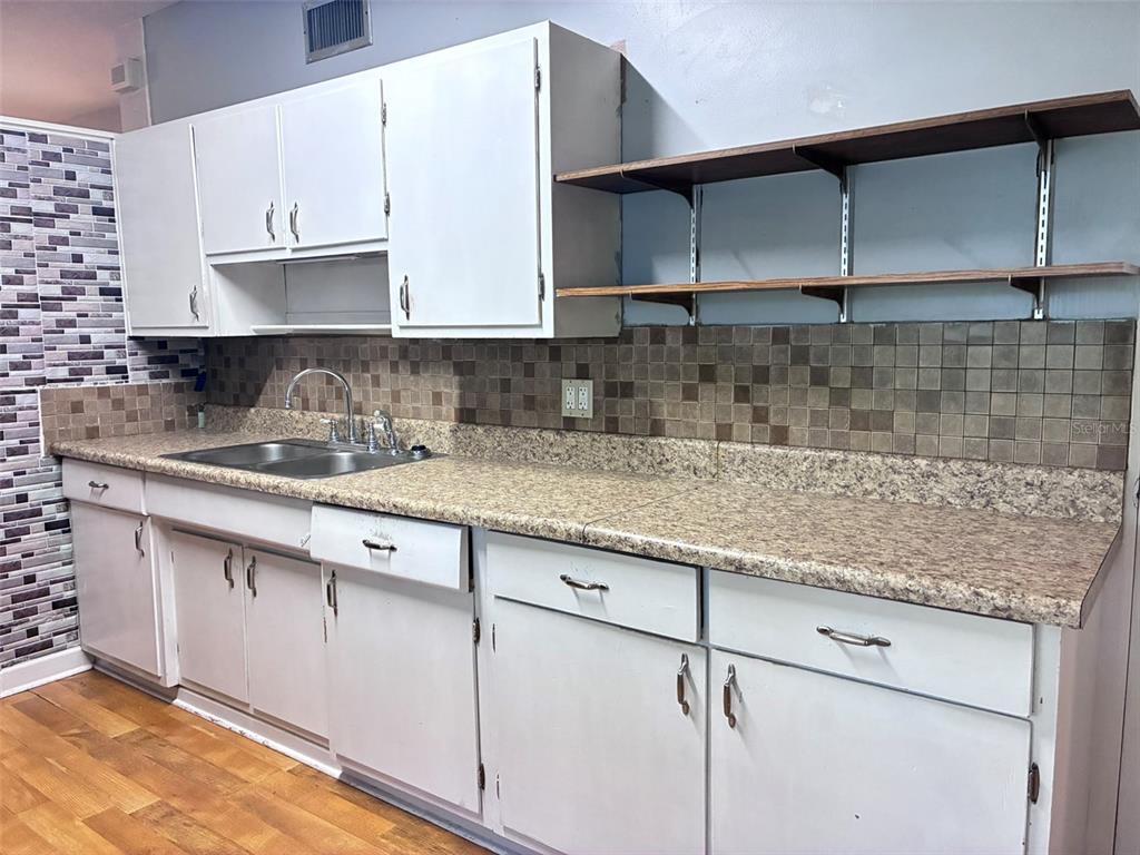 A kitchen features white cabinets, a speckled laminate countertop, and a tiled backsplash — 120 CLUB ROAD, SANFORD, FL