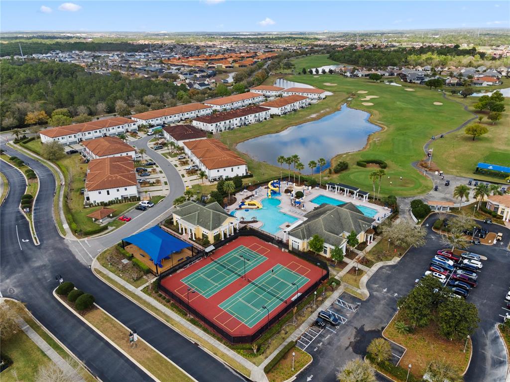 An aerial view shows a community pool, tennis courts, and residential buildings near a lake — 3050 CAMDEN WAY, DAVENPORT, FL