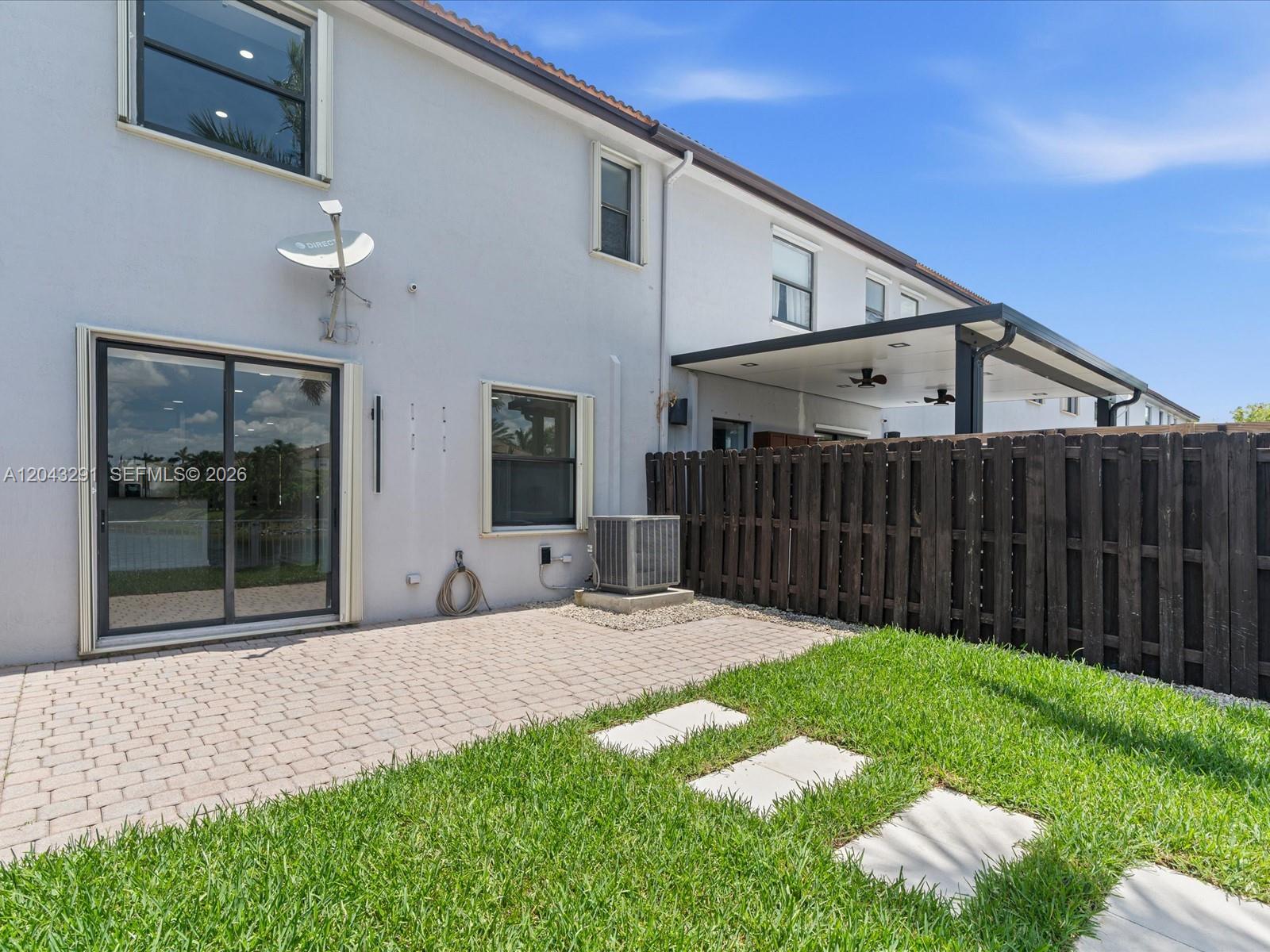 A backyard features a paved patio, a grassy lawn, and a covered outdoor living area — 11628 NW 87th Ln # 11628, Doral FL 33178, DORAL, FL