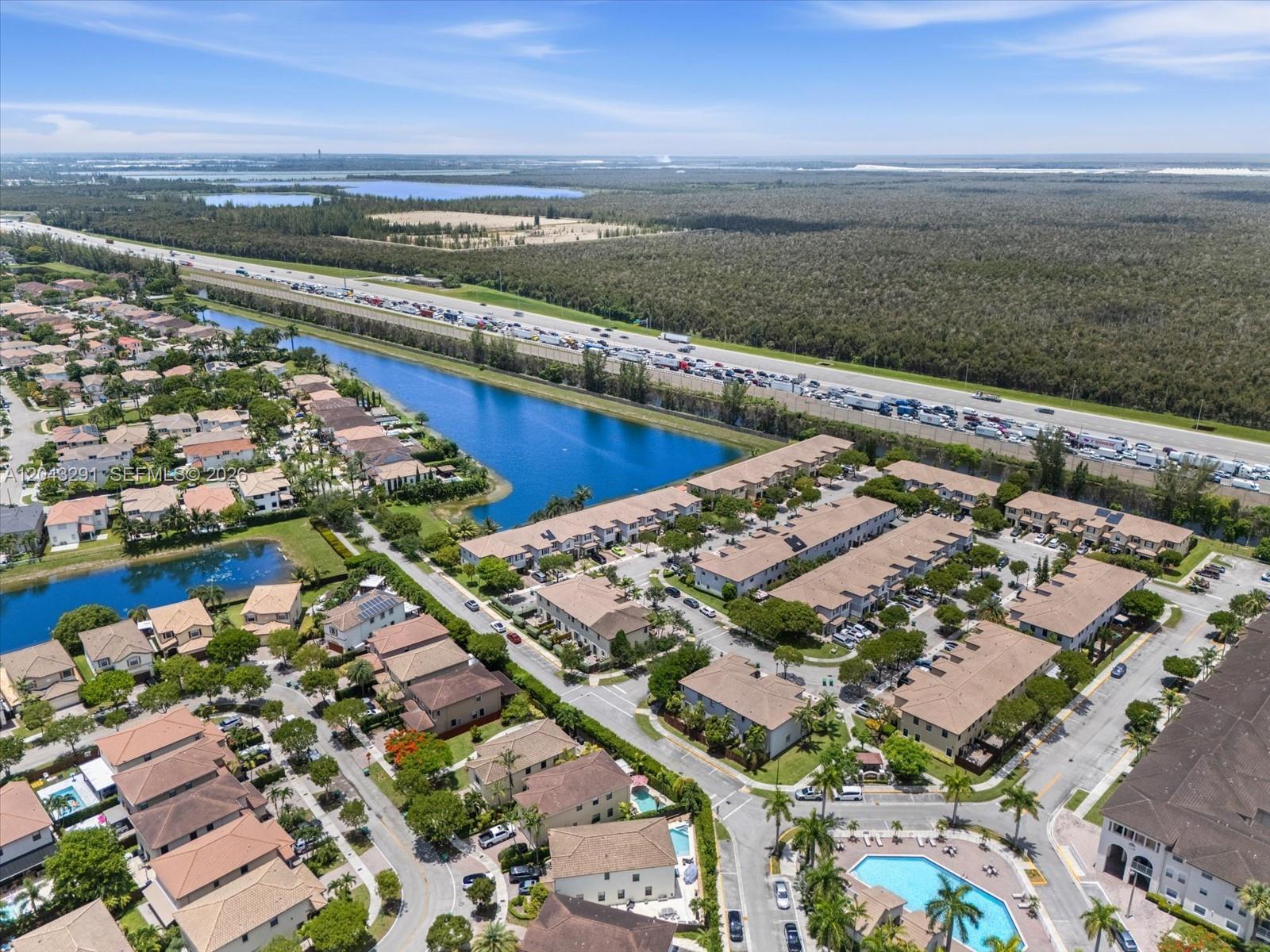 An aerial view shows a residential community with townhouses, a swimming pool, and a nearby highway — 11628 NW 87th Ln # 11628, Doral FL 33178, DORAL, FL
