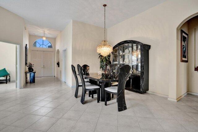 A dining room features a black table and chairs under a crystal chandelier — 15334 Fiorenza Circle, Delray Beach FL 33446, DELRAY BEACH, FL