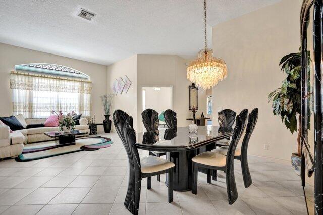 A dining area with a black table and chairs sits adjacent to a living room — 15334 Fiorenza Circle, Delray Beach FL 33446, DELRAY BEACH, FL