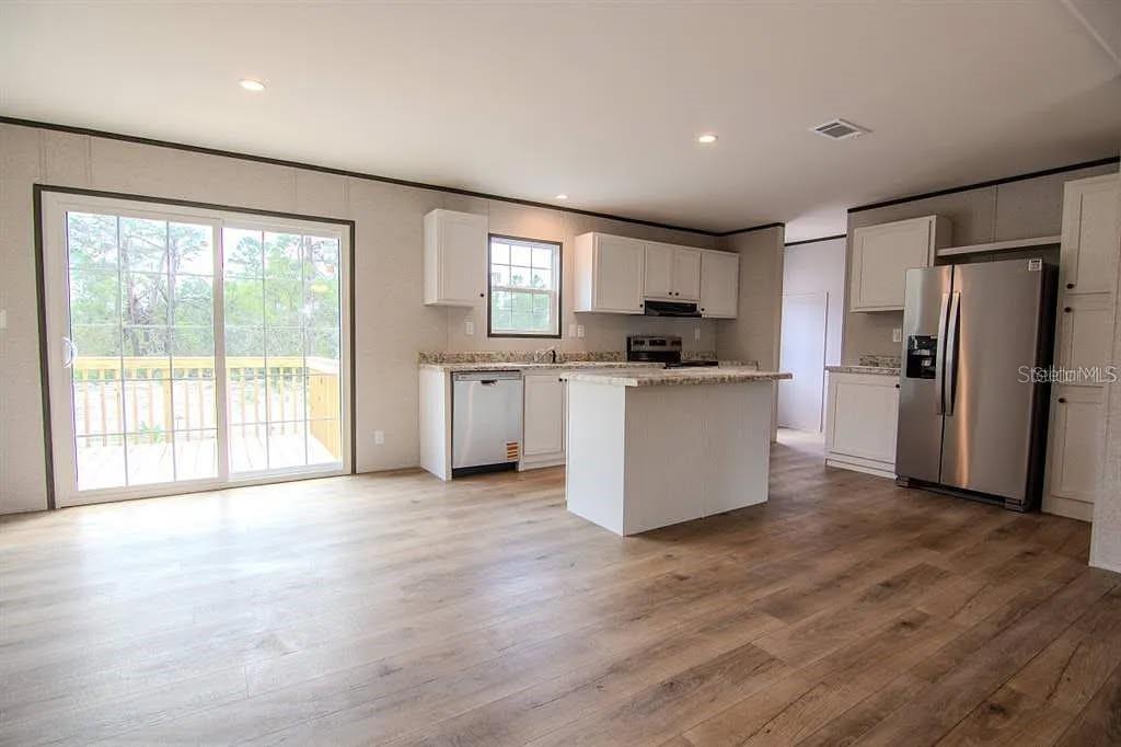 A kitchen with white cabinets, stainless steel appliances, and an island opens to a deck — 16854 NW 254TH STREET, OKEECHOBEE, FL