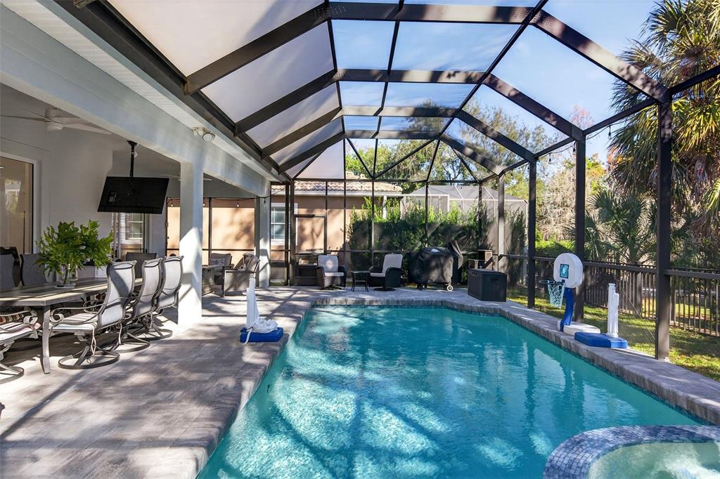 A swimming pool with a spa is enclosed by a screened lanai with outdoor seating — 8111 SANTA ROSA COURT, SARASOTA, FL
