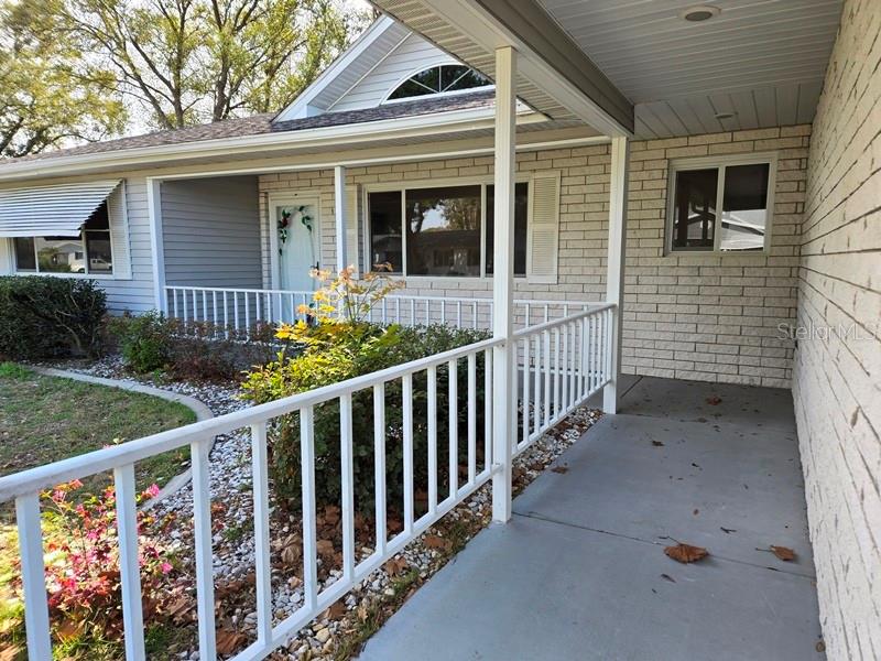 A covered front porch with a white railing leads to the home's entrance — 11510 SW 85TH COURT, OCALA, FL