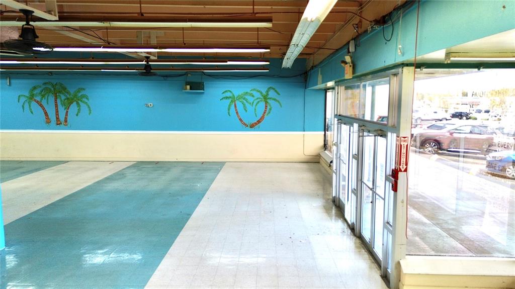 An empty commercial space features blue walls with painted palm trees and tile flooring — 1091 W MAIN STREET, AVON PARK, FL