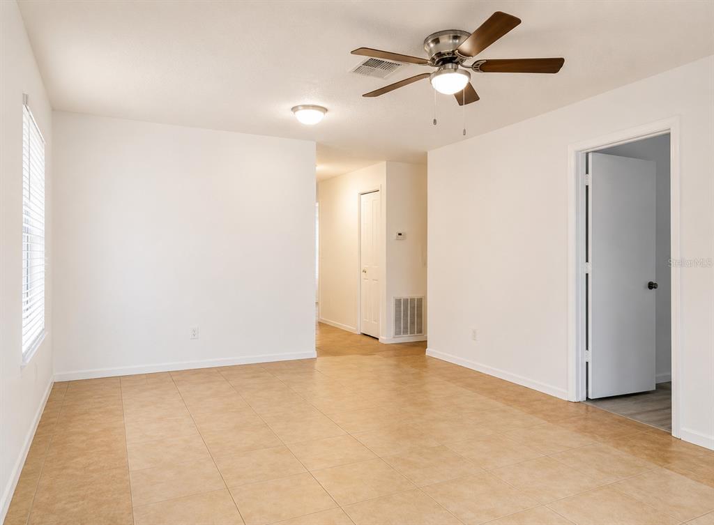 An empty room features white walls, tan tile flooring, a ceiling fan, and a doorway — 4808 HO WIL LANE, BRADENTON, FL