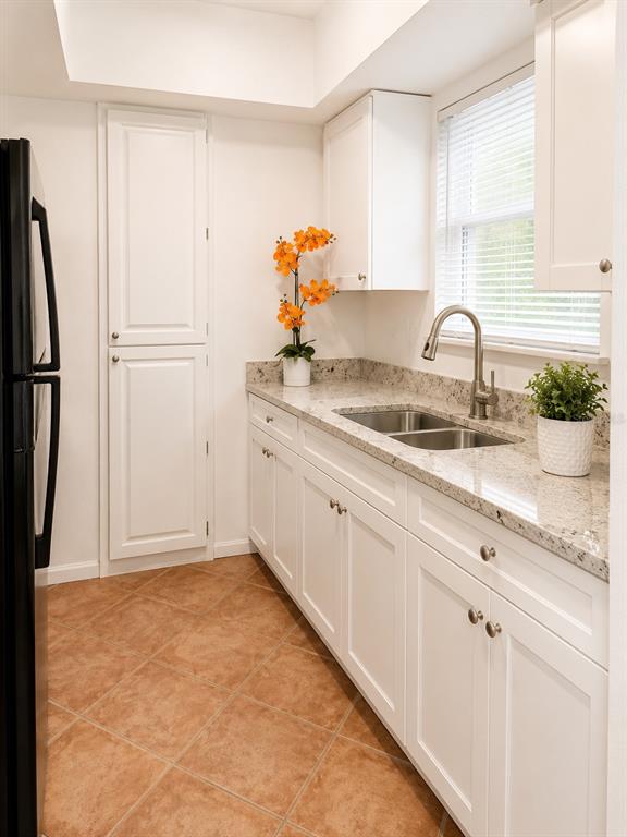 A kitchen features white cabinets, granite countertops, a stainless steel sink, and tiled flooring — 4808 HO WIL LANE, BRADENTON, FL