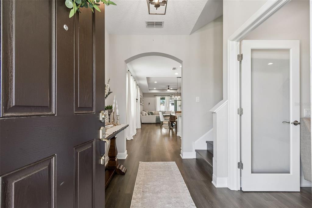 A view from an open front door into a hallway with wood flooring and stairs — 19779 MORSANI ROAD, LUTZ, FL