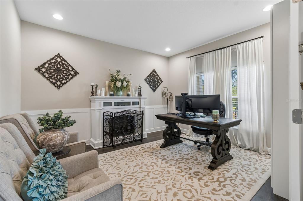 A home office features a fireplace, a dark wood desk, and two upholstered armchairs — 19779 MORSANI ROAD, LUTZ, FL