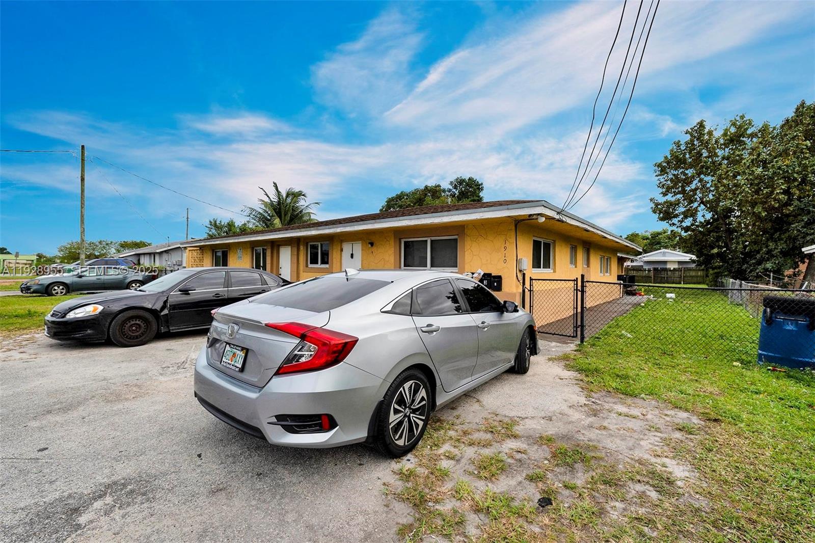 A yellow single-story house with a silver sedan parked in the gravel driveway — 1910 NW 72nd St, Miami FL 33147, MIAMI, FL