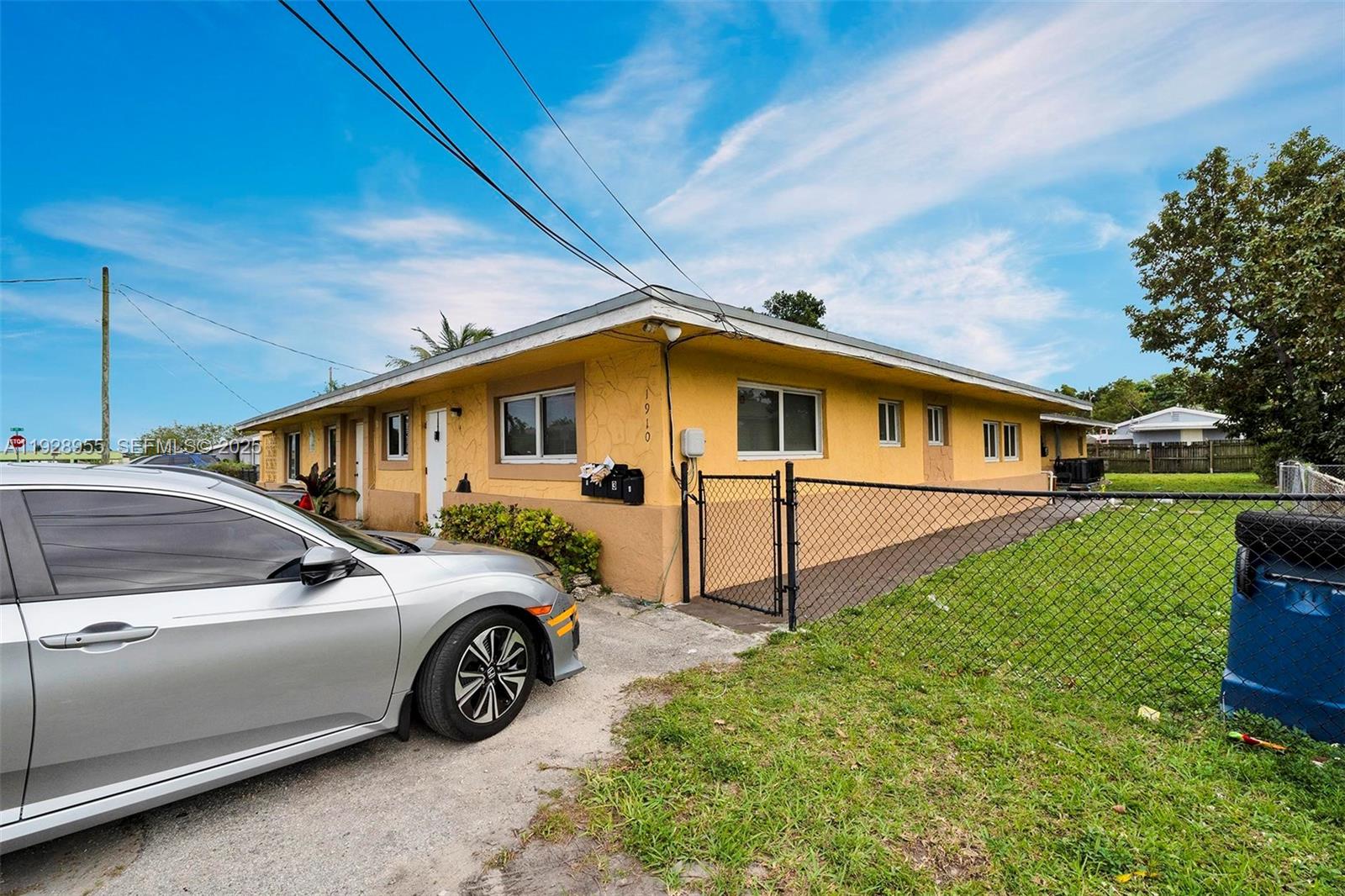 A yellow single-story building with a chain-link fence and a silver car parked outside — 1910 NW 72nd St, Miami FL 33147, MIAMI, FL
