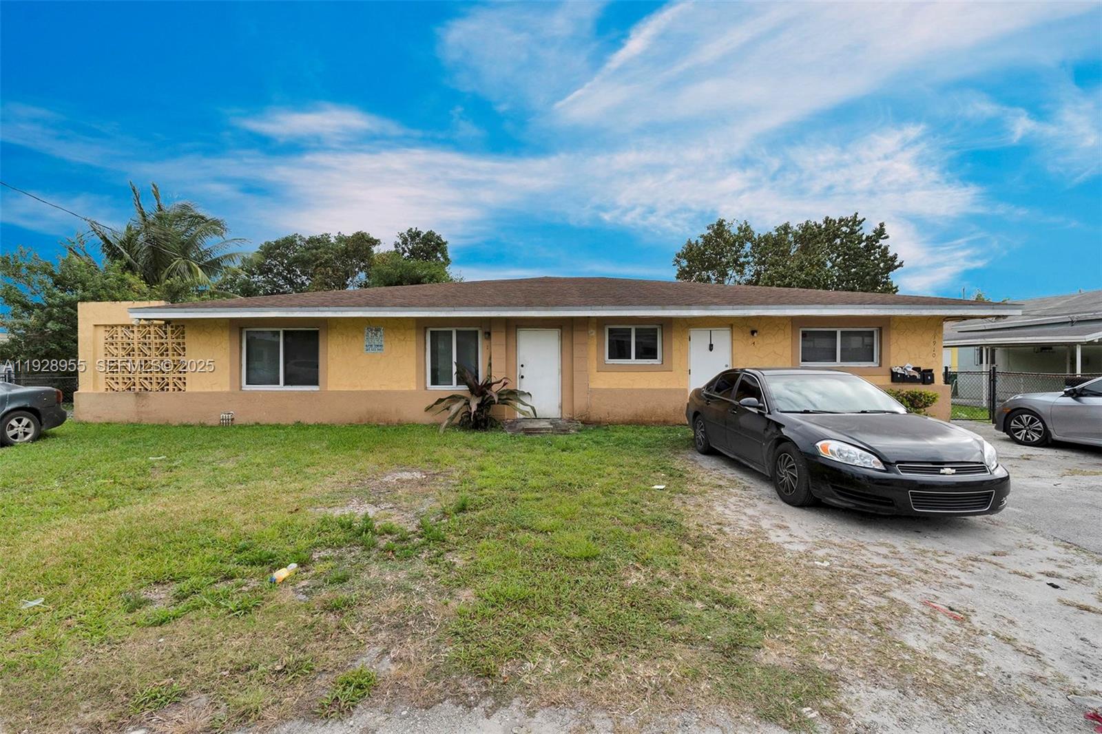 A single-story house with a tan stucco exterior, two front doors, and a gravel driveway — 1910 NW 72nd St, Miami FL 33147, MIAMI, FL