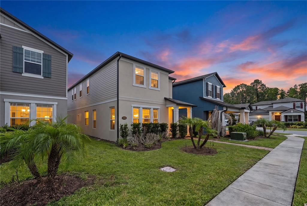 A two-story house with beige siding and a front lawn at sunset — 12597 ENCORE AT OVATION WAY, WINTER GARDEN, FL