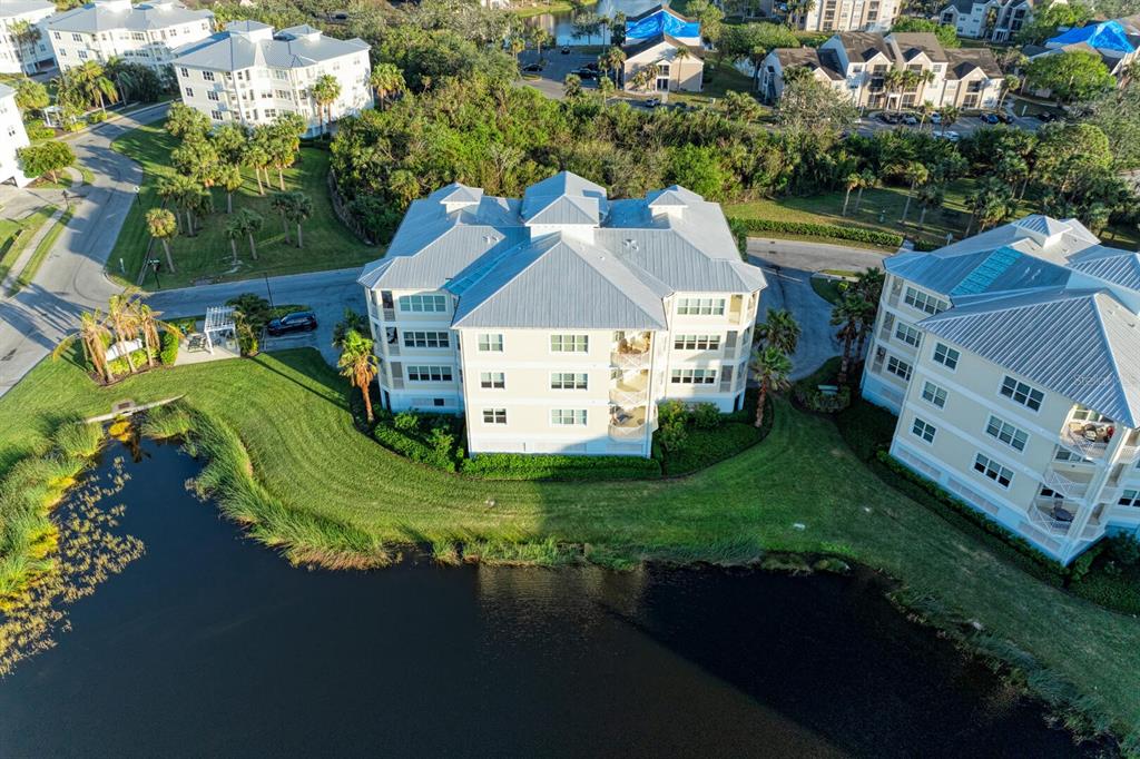 An aerial view shows two multi-story apartment buildings situated beside a pond and greenery — 3404 79TH STREET CIRCLE W UNIT 203, BRADENTON, FL