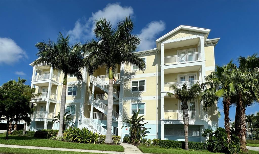 A multi-story apartment building with yellow siding, white balconies, and palm trees in front — 3404 79TH STREET CIRCLE W UNIT 203, BRADENTON, FL