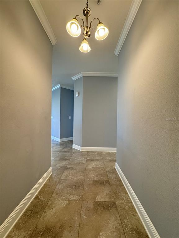 A hallway with tile flooring, gray walls, and a three-light chandelier — 3404 79TH STREET CIRCLE W UNIT 203, BRADENTON, FL