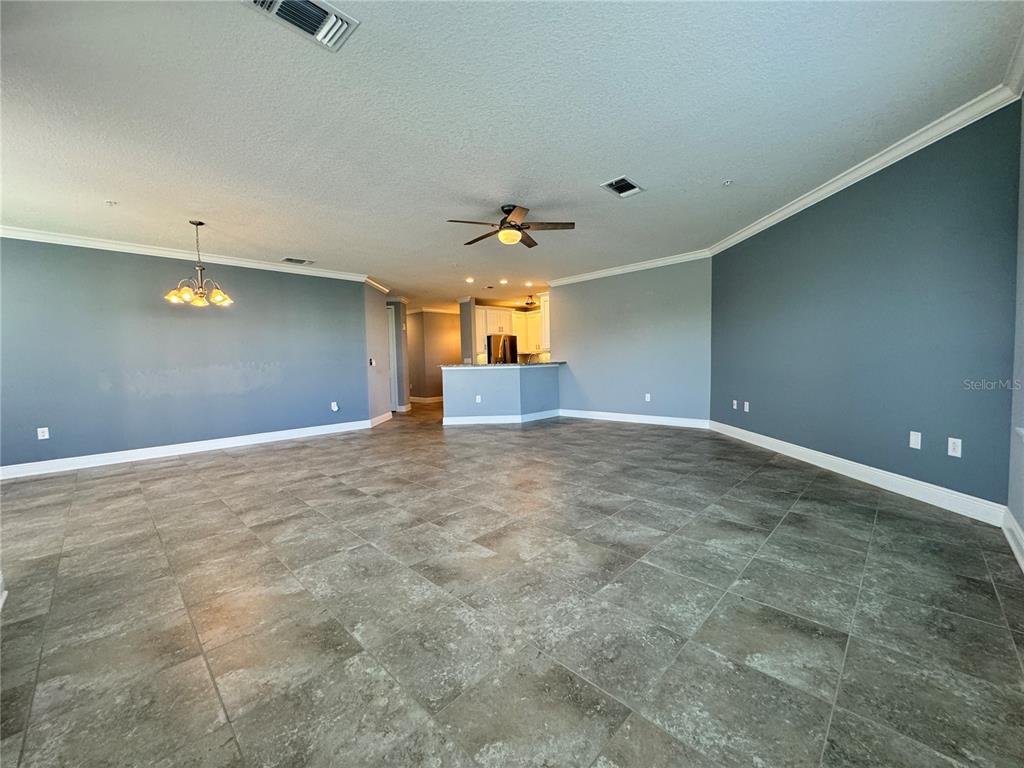 An open-concept living area features gray walls, large floor tiles, and a kitchen island — 3404 79TH STREET CIRCLE W UNIT 203, BRADENTON, FL