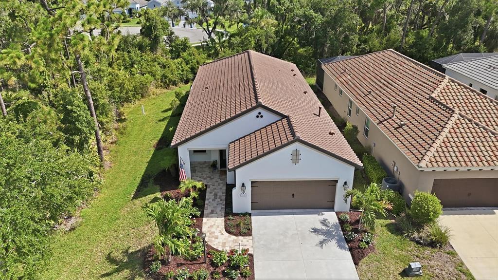 An aerial view shows a suburban neighborhood with houses, ponds, and surrounding wooded areas — 12946 TRUE BLUE CIRCLE, BRADENTON, FL