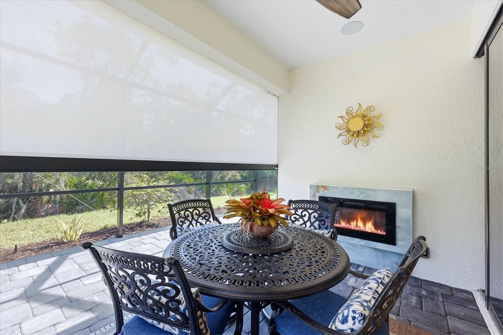 A covered patio features a dining set, an electric fireplace, and a retractable privacy screen — 12946 TRUE BLUE CIRCLE, BRADENTON, FL