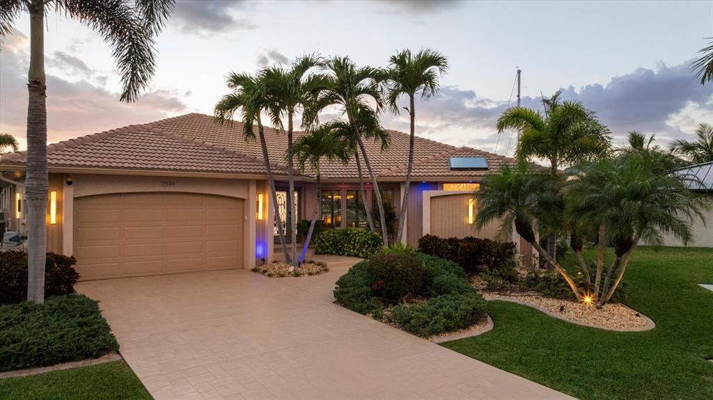A paved driveway leads to a single-story house exterior at dusk with palm trees — 2544 RIO LISBO COURT, PUNTA GORDA, FL