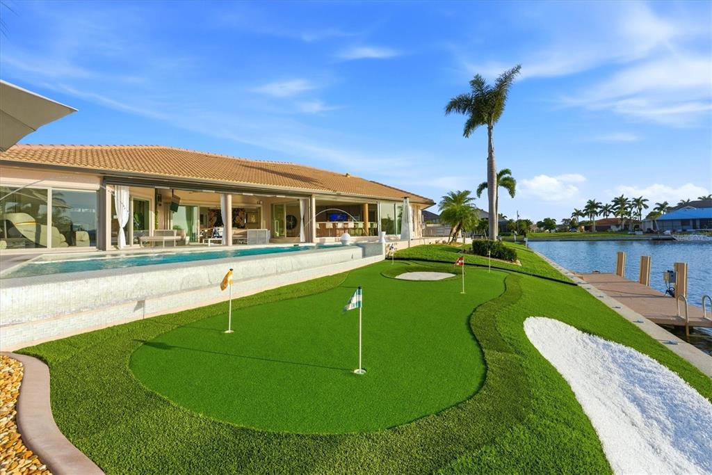 A backyard at night features a putting green, a swimming pool, and a patio area — 2544 RIO LISBO COURT, PUNTA GORDA, FL