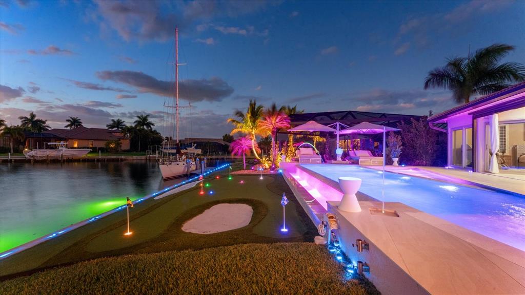 A backyard features a putting green, a swimming pool, and a dock along the water — 2544 RIO LISBO COURT, PUNTA GORDA, FL