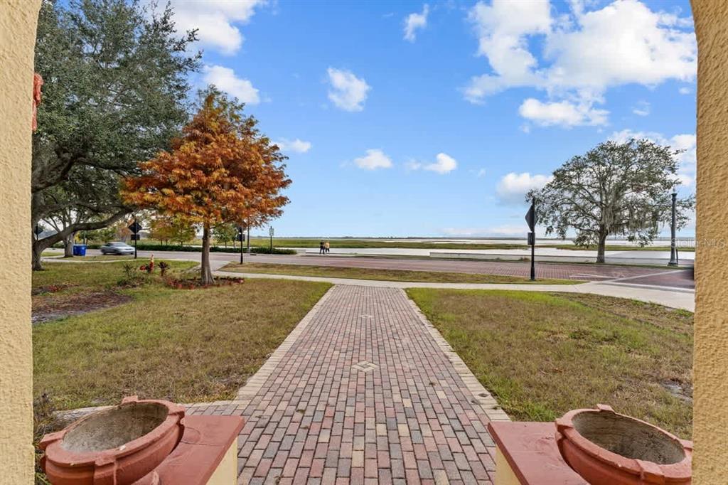 A brick walkway leads from a porch toward a street and a waterfront view — 304 LAKESHORE BOULEVARD, KISSIMMEE, FL
