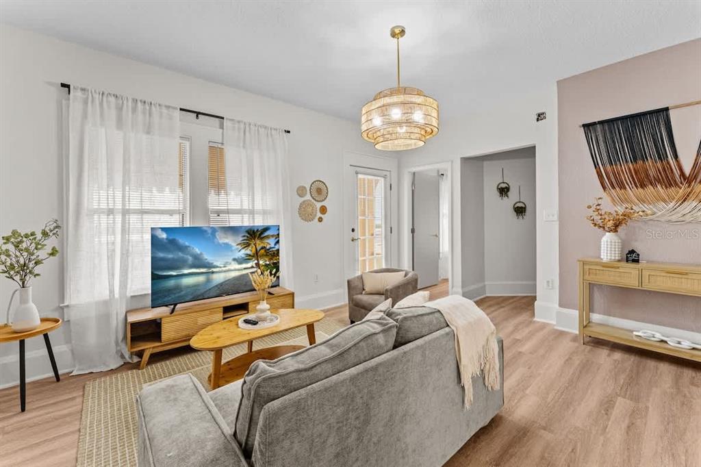 A living room features a gray sofa, a wood media console, and a tiered chandelier — 304 LAKESHORE BOULEVARD, KISSIMMEE, FL