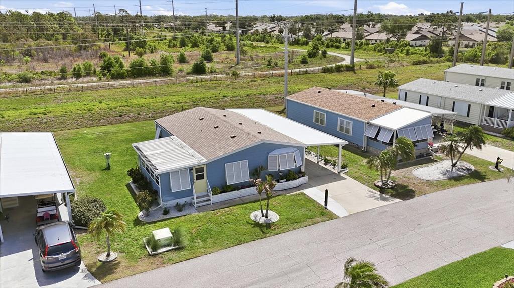 An aerial view shows two blue mobile homes with carports and palm trees on a street — 727 BUTTERFIELD CIRCLE, ENGLEWOOD, FL
