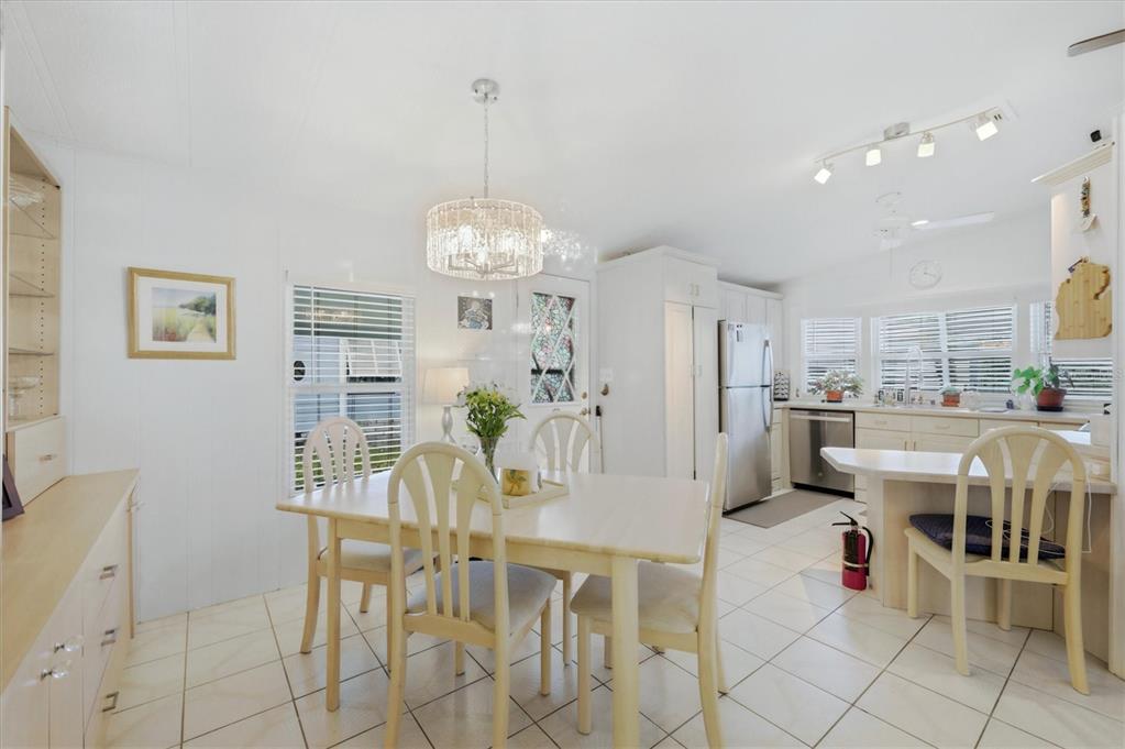 A dining area with a crystal chandelier, light wood furniture, and white tile flooring — 727 BUTTERFIELD CIRCLE, ENGLEWOOD, FL