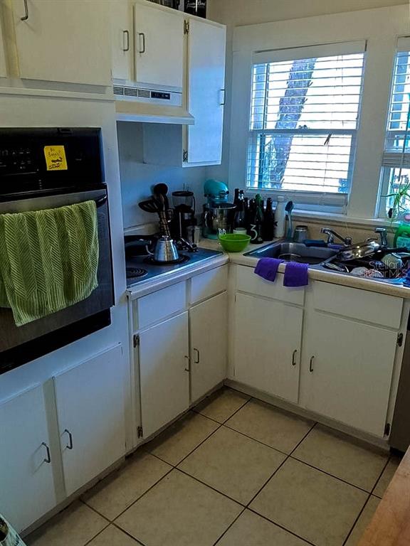 A kitchen features white cabinets, a wall oven, a tiled floor, and a window — 1210 HIGHLAND STREET S, ST PETERSBURG, FL